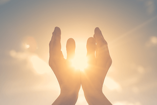 Hands raised to the sky encompassing the sun