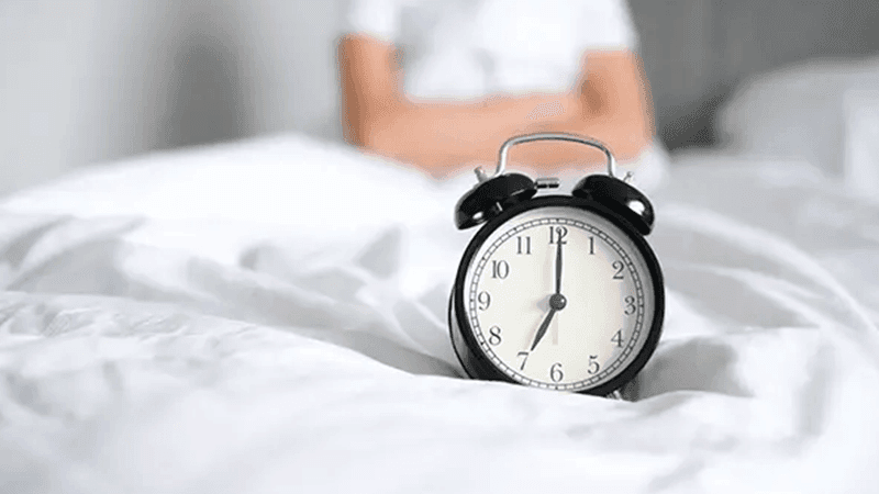 An alarm clock on a bed
