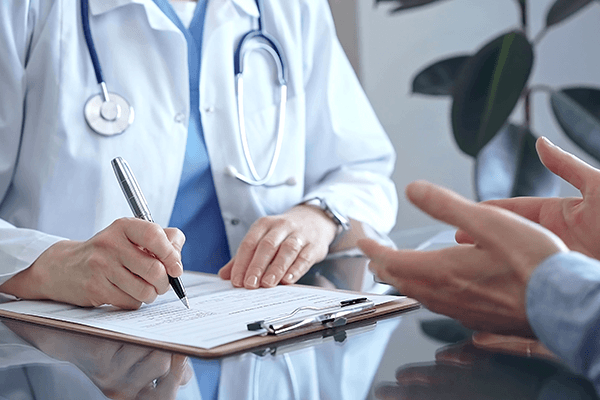 A doctor discussing addiction signs with a patient and writing on a clipboard