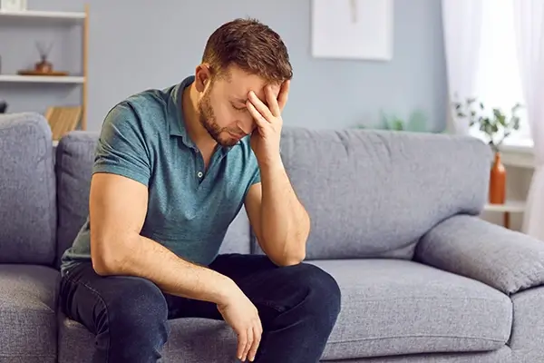 A man sitting at a couch with his head in his hand