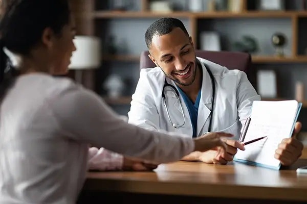 A doctor reviewing results on a clipboard with a patient and smiling