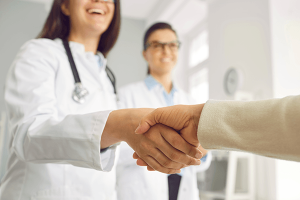 A physician warmly shaking hands with a patient