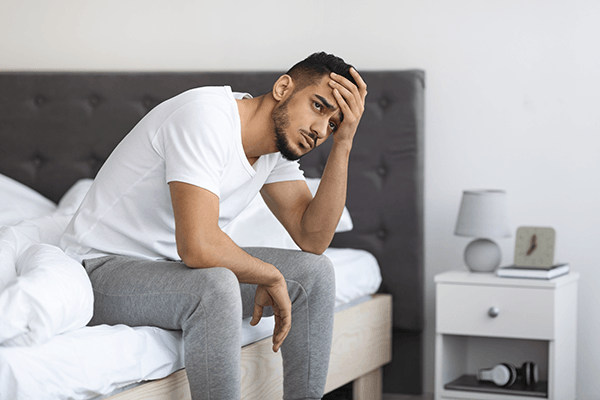 A man sitting up in bed with sleep deprivation due to chronic lyme disease