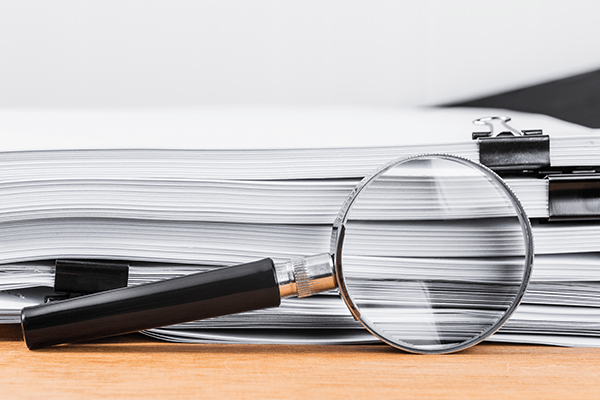 A magnifying glass by a stack of papers