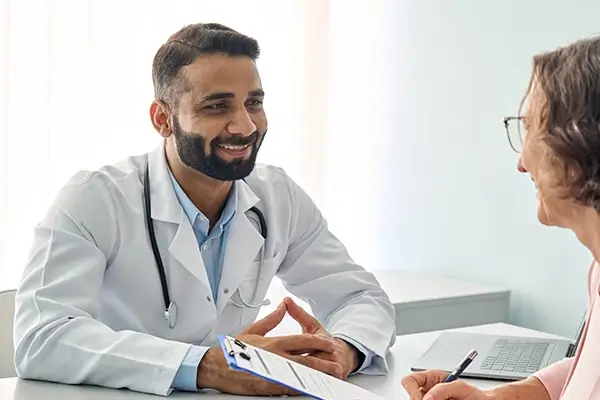 A doctor smiling at a patient who is filling out a form