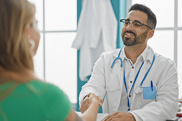 A doctor happily shaking hands with a patient