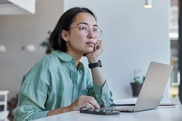A woman at her computer looking into the distance distractedly