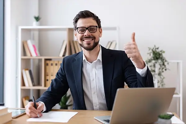A man at his workstation giving a thumbs up