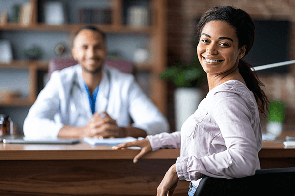A patient sitting with a doctor and smiling.